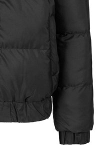 Jachetă puffer neagră cu textură matlasată, manșoane și tiv elastic și buzunare laterale. Materialul pare ușor, dar izolat.