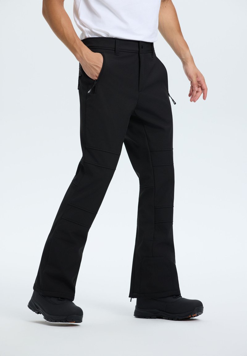 Czarne spodnie o dopasowanym kroju, z zamykanymi na zamek bocznymi kieszeniami, płaskimi szwami i wzmocnionym dołem. Wykonane z trwałej, elastycznej tkaniny.