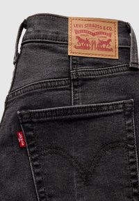 Mørkegrå Levi's jeans baglomme med brun lædermærkat og rød Levi's stofetiket i sidesøm.