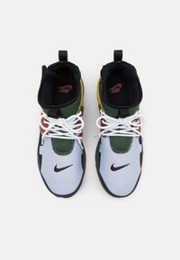 Sportovní boty Nike s vysokým střihem. Mají vícebarevné panely: bílá, zelená, oranžová a černá. Zapínají se na bílé tkaničky.