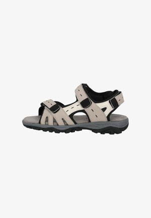 Beige Sandalen für den Außenbereich mit schwarzen Akzenten, ausgestattet mit verstellbaren Klettverschlüssen, offenem Design und strukturierter Gummisohle für besseren Halt.