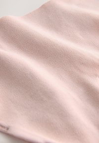 Light pink ribbed fabric with a soft texture, featuring subtle variations and slight sheen. Fabric drapes smoothly, showcasing its flexibility.