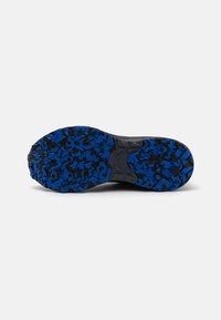 Semelle de chaussure de sport noire avec un design texturé. Motif de couleur bleu et noir avec une bande de roulement prononcée pour une meilleure adhérence.