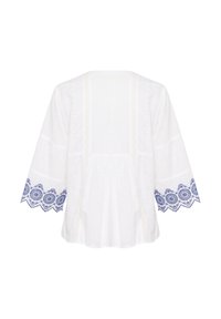 Witte geborduurde blouse met decoratieve blauwe bloempatronen op de mouwen. Heeft een losvallende pasvorm, ronde halslijn en een gestructureerde stof.