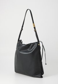 Large black leather tote bag with a drawstring closure, smooth texture, gold-tone hardware, and adjustable shoulder strap.