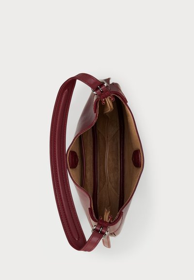 Red leather handbag with a structured design, featuring a top opening, an inner divider, smooth texture, and metal hardware accents.