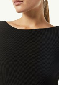 Schwarzes, geripptes Strickoberteil mit weitem, flachem Ausschnitt und glatter Textur. Nahaufnahme, die subtile vertikale Linien und eine taillierte Passform zeigt.