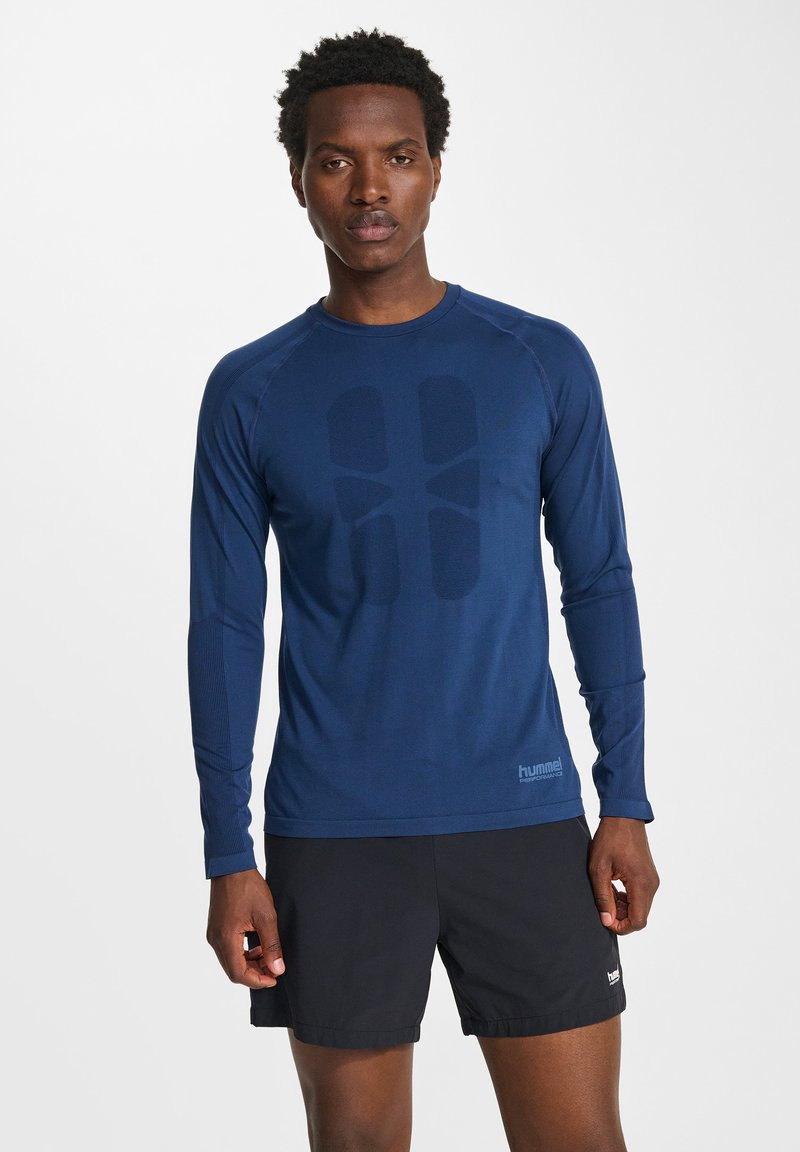 Långärmad sporttröja i mörkblå, med en texturerad mönster på framsidan, rund hals och figurnära design.