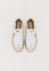 Weiße Sneaker mit einer glatten Oberseite, Gummi-Sohle, strukturierten grauen Wildlederelementen und bunten Mustern an der Ferse. Mit Schnürsenkeln.