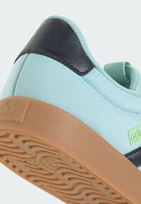 Jasnoniebieski tenisówka z płótna z teksturowaną gumową podeszwą, ciemnoniebieskimi skórzanymi akcentami oraz zieloną etykietą marki po boku.