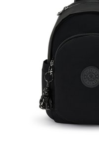 Sac à dos en nylon noir avec un patch logo rond, texture lisse, et un porte-clés en forme d'ours noir décoratif attaché à la fermeture éclair.