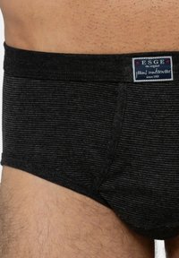Slip da uomo a righe nere con un morbido elastico in vita. Presenta un'etichetta con i dettagli del marchio, mostrando un design aderente e un tessuto strutturato.