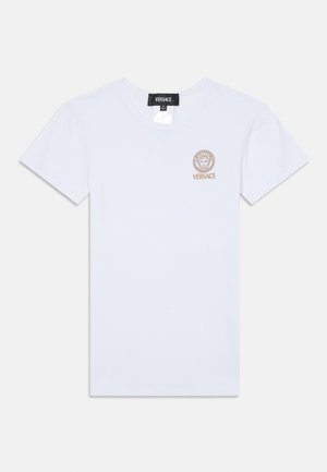 Balta medvilninė marškinė su trumpomis rankovėmis, kuriuose yra auksinė Medūzos emblema ir žodis "VERSACE" kairėje krūtinės pusėje. Paprasta apvalia iškirpte.