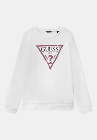 Sudadera blanca de manga larga y cuello redondo. Presenta un logo triangular de purpurina rosa con "GUESS U.S.A." y texto en su interior.