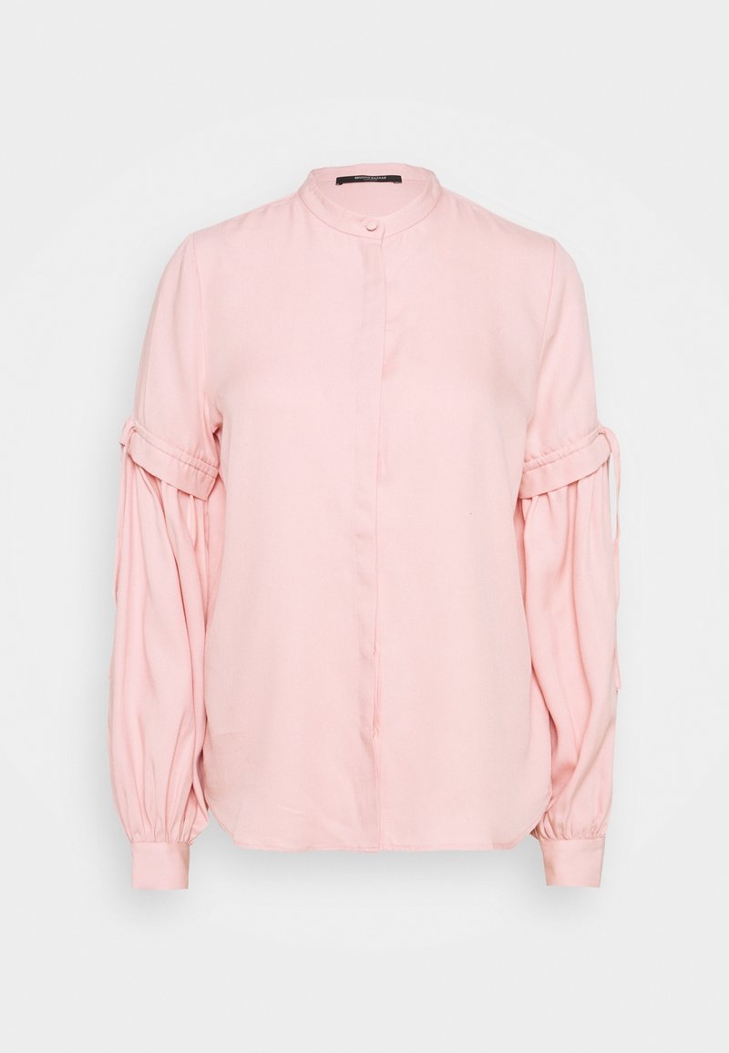 Blouse rose clair avec un col montant, un devant boutonné et des manches bouffantes ornées de détails froncés et de poignets élastiqués. Texture du tissu lisse.