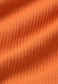 Rippstoff in leuchtendem Orange, mit subtiler Textur und eng beabstandeten vertikalen Linien, die ein weiches und dehnbares Erscheinungsbild erzeugen.