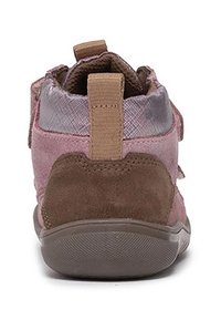 Tył różowo-brązowego dziecięcego trampka z teksturowaną podeszwą, wyściełanym kołnierzem i beżową pętelką na pięcie.