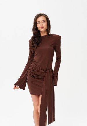 Braunes langärmliges Kleid mit geraffter Taillenpartie und gebundenem Akzent. Glattes Material mit schmaler Silhouette und ausgestellten Ärmelabschlüssen.