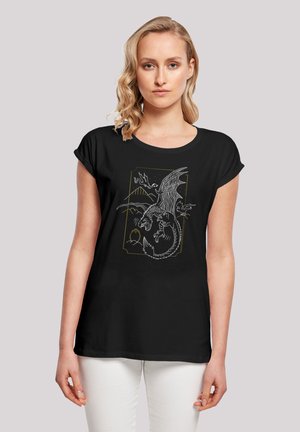 Schwarzes T-Shirt mit kurzen Ärmeln, das ein Drachenmotiv in Weiß und Gold zeigt, ergänzt durch Details von Bergen und einem Ei. Glattes Material, entspannte Passform.