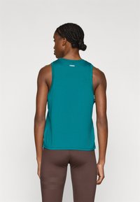 Τιρκουάζ αθλητική μπλούζα χωρίς μανίκια με στρογγυλή λαιμόκοψη και λογότυπο στην πλάτη· διαθέτει αμάνικο σχέδιο και ελαφρύ ύφασμα.