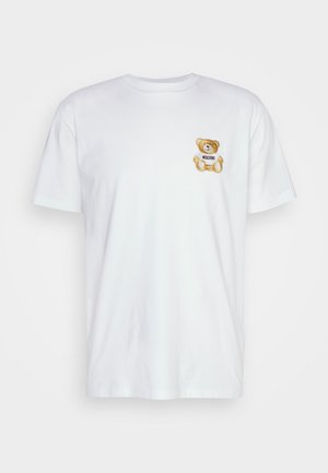 Camiseta de algodón blanca con un oso de peluche bordado y una etiqueta que dice "Moschino" en la parte izquierda del pecho. Mangas cortas, escote redondo.