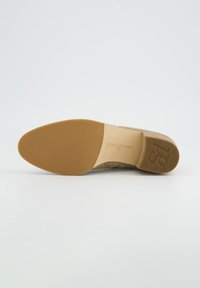 Zapato de ante beige con punta redondeada, suela de goma suave en tono marrón y logo grabado en la plantilla. Diseño simple y elegante.