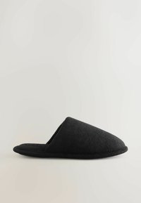 Chausson noir en tissu doux à dos ouvert avec bout fermé, présenté de profil sur un fond clair uni.