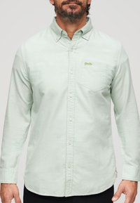 Lichtgroen overhemd met lange mouwen van zachte stof, met een button-down kraag, een borstzak en witte knopen. Groen logo op de zak.