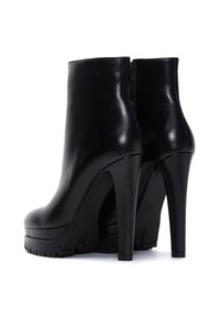 Botas de cuero negro hasta el tobillo con tacón alto, suela texturizada, acabado suave y cierre de cremallera en la parte posterior. El diseño de plataforma añade altura.