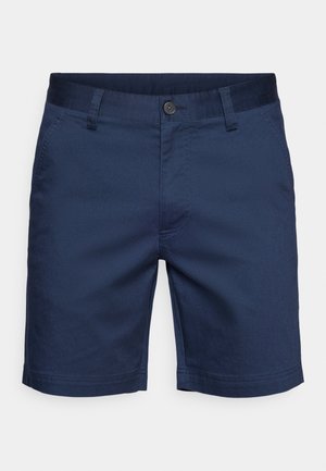 Calções azul-marinho feitos de tecido leve, com fecho de botão, passantes para cinto e bolsos laterais. Costura limpa e mínima nas bainhas.