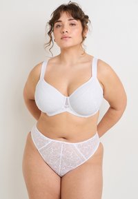 Ensemble de soutien-gorge en dentelle blanche et de culottes taille haute, avec un motif floral, des accents transparents, des bonnets rembourrés et des bretelles larges. Texture douce et tissu extensible.