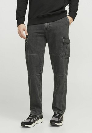 Pantalones cargo de mezclilla gris con costuras visibles, bolsillos laterales y un corte relajado, combinados con zapatillas en negro y gris.
