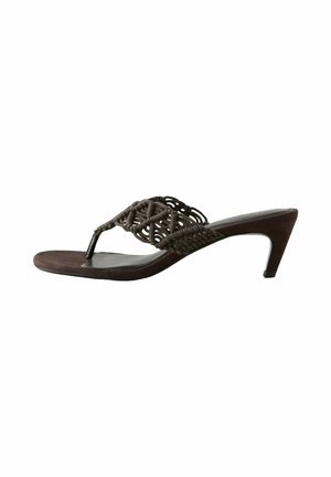 Kvinde iført løs, mørk lilla ærmeløs buksedragt med spaghetti-stropper, sorte sandaler, store øreringe og chunky armbånd.