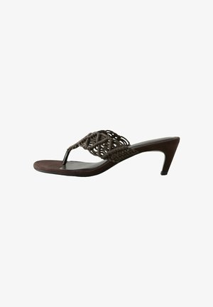 Kvinde iført løs, mørk lilla ærmeløs buksedragt med spaghetti-stropper, sorte sandaler, store øreringe og chunky armbånd.