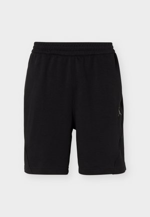 Pantaloni scurți sport negri până la genunchi, cu talie elastică și logo discret lateral pe un fundal simplu și deschis.