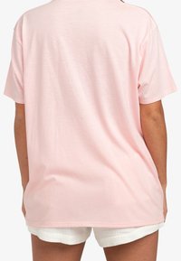 Camiseta de algodón de color rosa claro con un ajuste relajado, mangas cortas y cuello redondo. Textura suave, sin patrones ni acentos visibles.