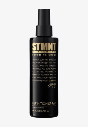 Spruzzatore nero con finitura opaca, scritte dorate. Etichetta con la dicitura "STMNT GROOMING GOODS DEFINITION SPRAY" e una firma scritta a mano. 200 mL.