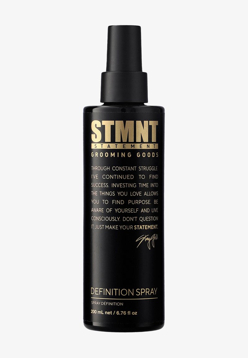 Svart sprayflaska med matt finish och guldtext. Etiketten lyder "STMNT GROOMING GOODS DEFINITION SPRAY" med en handskriven signatur. 200 ml.
