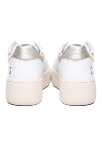 Sneaker bianca con un accento metallico argento sul tallone, caratterizzata da una suola intermedia testurizzata di un bianco sporco e una tomaia in pelle liscia. Design con punta rotonda.
