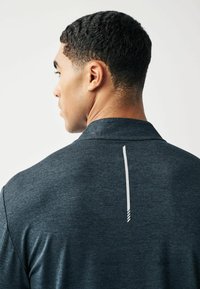 Dunkelgraues Poloshirt aus strukturiertem Stoff, mit einem weißen vertikalen Streifen und drei Akzentlinien am Kragenrücken.