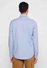 Lichtblauwe overhemd met knopen, gemaakt van geweven stof, met een klassieke kraag, lange mouwen en manchetten met één knoop.
