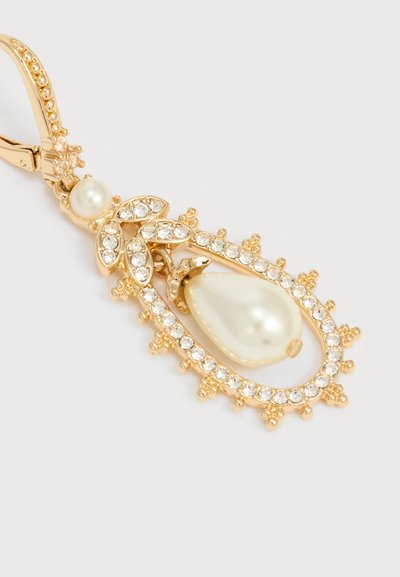 Σκουλαρίκι σε χρυσή απόχρωση με μικρούς διάφανους κρυστάλλους, καρφίτσα με πέρλα, φύλλα επενδυμένα με κρύσταλλα και μεγάλο κρεμαστό ψεύτικης πέρλας σε σχήμα σταγόνας.