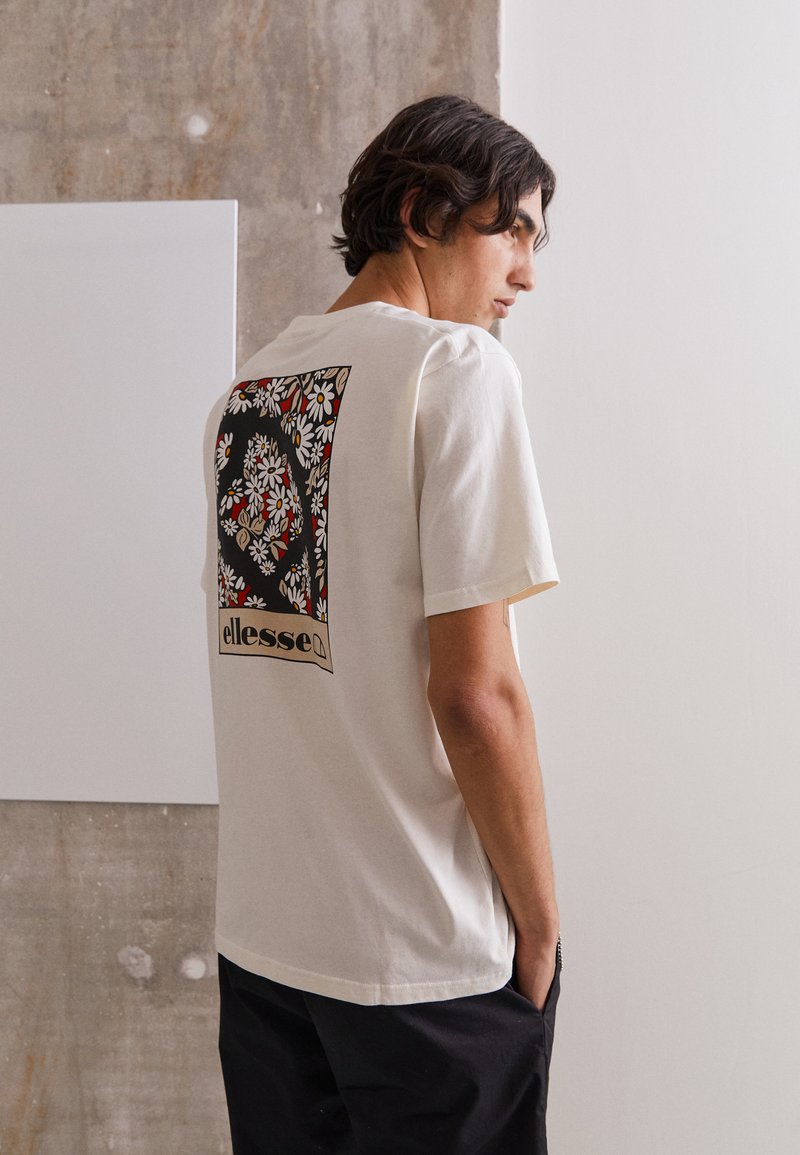 Cremefarbener Baumwoll-T-Shirt mit floraler Grafik auf der Rückseite in Rot, Gelb und Schwarz. Lockere Passform mit kurzen Ärmeln.