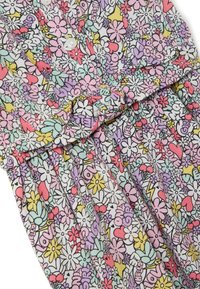 Abito floreale in tessuto leggero, con una stampa multicolore di fiori, cuori e forme fantasiose; include bottoni bianchi e pieghe.