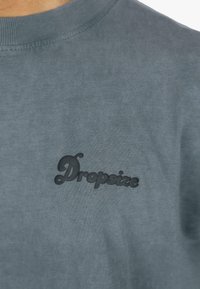 Sivá bavlnená mikina s okrúhlym výstrihom a textúrovaným čiernym logom "Dropsize" na hrudi. Hladká tkanina a neformálny dizajn.
