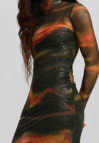 Figurnära klänning i svart, glittrigt tyg med ett livfullt abstrakt mönster i rött, orange och grönt; långärmad.