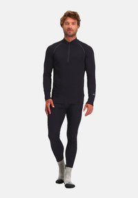 Zwarte longsleeve shirt met halve rits en aansluitende zwarte legging. Sokken zijn grijs met een patroon aan de manchet, allemaal gemaakt van rekbare stof.
