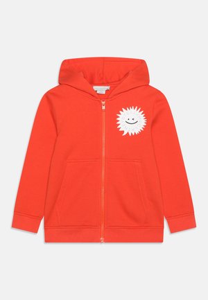 Sweat à capuche zippé orange vif pour enfants, avec capuche, poches avant et motif de soleil blanc avec sourire et texte sur le côté gauche de la poitrine.