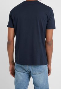 Tmavě modré bavlněné tričko s krátkými rukávy a okrouhlým výstřihem, zobrazené zezadu. Má pohodlný střih a měkkou strukturu.