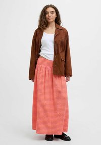 Brun ruskindsfringet jakke, hvid tanktop og lang pinkternet nederdel. Sorte sko fuldender outfittet. Bemærkelsesværdige frynser på jakken.